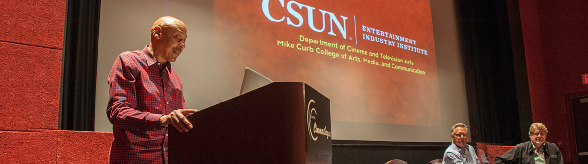a faculty member speaks inside the csun theatre 