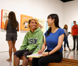 two students sit inside and talk inside the art gallery