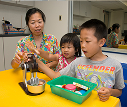 children play with toys as their mother watches them