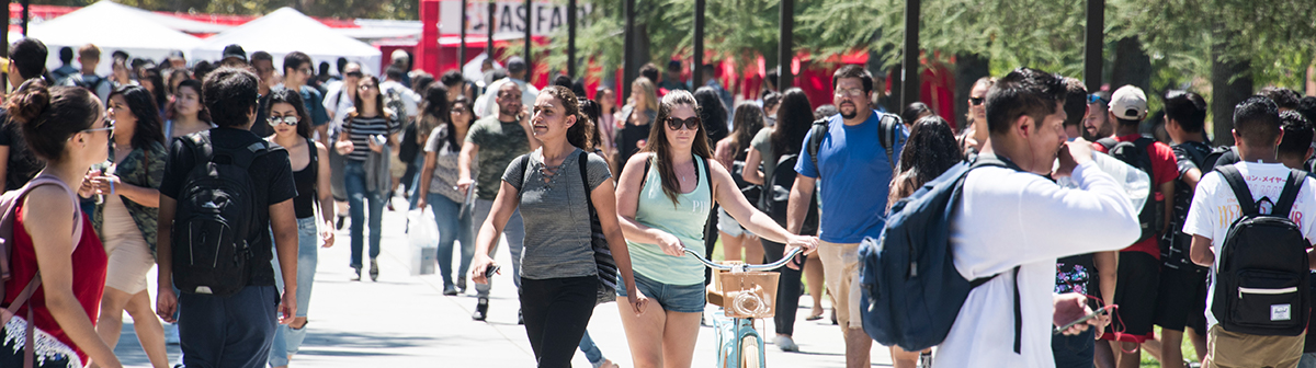 a student walks her bike through a crowd 