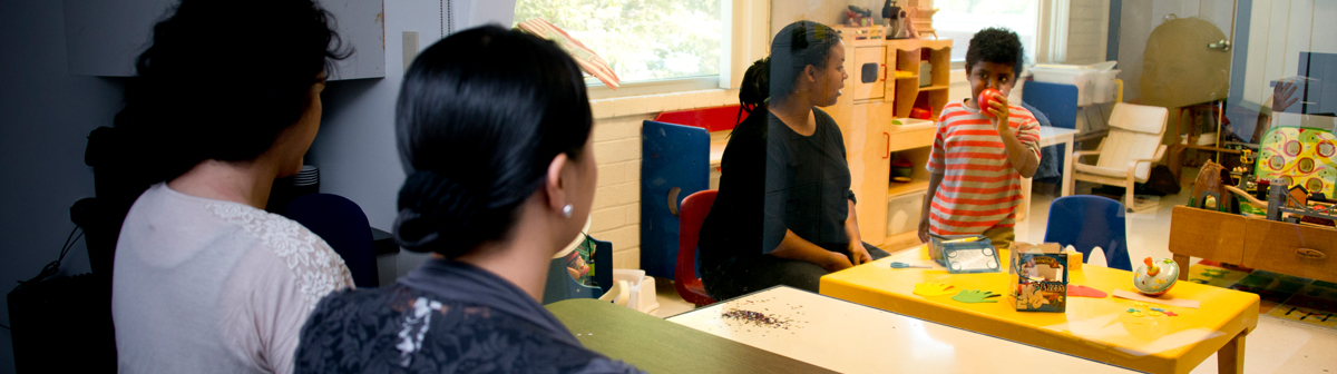 a student and a teacher watch a small child play with toys in a classroom setting