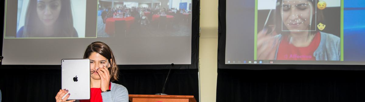 a student uses an ipad to demonstrate a project on a stage