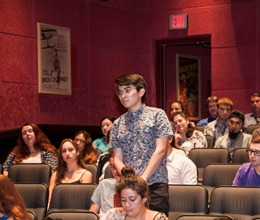 a student stands inside a theatre to speak