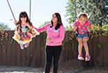 Student playing on the swings with children.