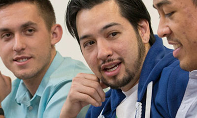 Three Students in class talking to each other.