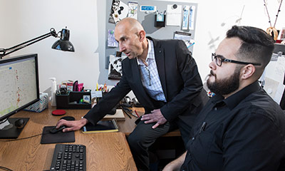 Professor looking at a computer with a student.