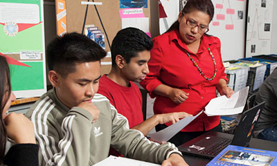 A Teacher looking over students in class.