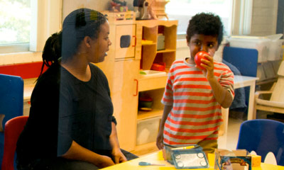 A Female adult sitting at a table with a Child. 