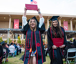 A graduate showing their Diploma after Commencement